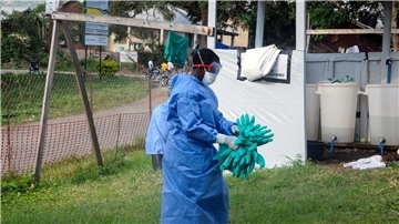 Ein Mitarbeiter in medizinischer Schutzkleidung trägt Schutzhandschuhe in einem Krankenhaus, in dem ein Ebola-Opfer isoliert wurde.