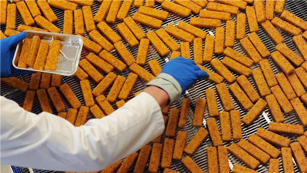 Ein Mitarbeiter kontrolliert Fischstäbchen in der Produktion eines Tiefkühlkost-Herstellers. Frozen Fish betreibt in Bremerhaven eine der größten Fischstäbchenfabriken. Dort wird am Mittwoch gestreikt.