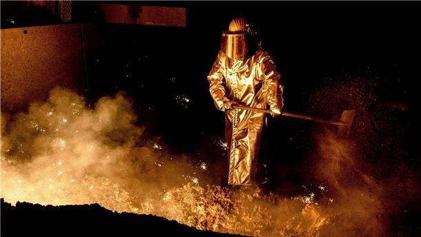 Industrie-Gewerkschaft fordert Vier-Tage-Woche Ein Mitarbeiter schaufelt im Stahlwerk Sand in eine Abstichrinne am Hochofen.