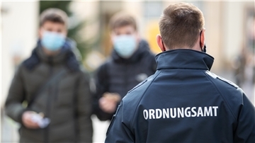 Ein Mitarbeiter vom Ordnungsamt patrouilliert in der Fußgängerzone an Passanten vorbei, die Mund-Nase-Bedeckung tragen. Durch Verstöße gegen die Corona-Verordnung kommt einiges an Bußgeldern zusammen.
