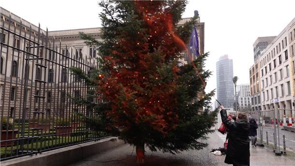 Ein Mitglied der Klimaschutzgruppe „Letzte Generation“ besprüht einen Weihnachtsbaum vor dem Bundesrat mit orangener Farbe.