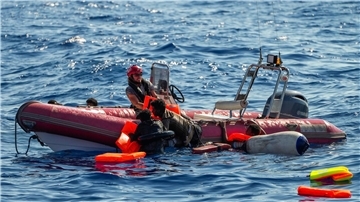Ein Mitglied der spanischen Nichtregierungsorganisation Open Arms hilft Migranten, an Bord zu kommen. Viele Minderjährige sterben während der Flucht.