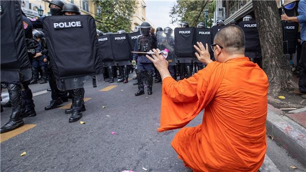 Ein Mönch hebt die Hände, als die Polizei Demonstrierende auseinandertreibt.