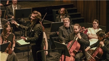 Ein Novum zum 1.Sinfoniekonzert „Neue Ufer“ des Philharmonischen Orchesters Bremerhaven: Unmittelbar neben Generalmusikdirektor Marc Niemann erleben zwei Gäste das Konzert aus neuer Perspektive mit: Sven Krause und Kim Ngan Nguyen auf ihren „heißen Stühlen“ zwischen Celli und Kontrabässen.
