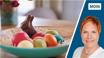 Ein Schoko-Osterhase nackt bei verschiedenen bunten Eiern. Für den Preis muss er mitarbeiten, findet die Autorin.