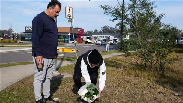 Ein Paar legt Blumen an einer Straßensperre in der Nähe des Unglücksortes nördlich von Sydney ab.