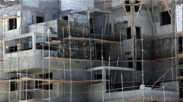 Israel genehmigt Bau von mehr als 5600 Siedlerwohnungen Ein Palästinenser zementiert in der großen jüdischen Siedlung Ma’ale Adumim im Westjordanland eine Mauer in einem Wohnkomplex. (Archivbild)