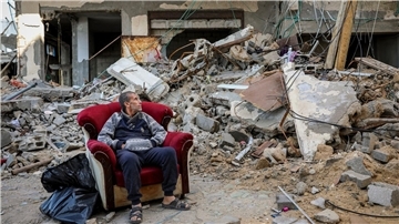 Ein palästinensischer Mann sitzt in einem Sessel vor einem zerstörten Gebäude in Gaza-Stadt.