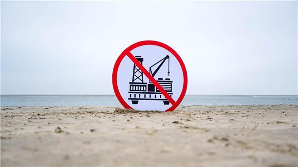 Gericht bestätigt Baustopp für Gasförderprojekt in Nordsee Ein Plakat gegen die geplante Erdgasförderung steht im Sand.