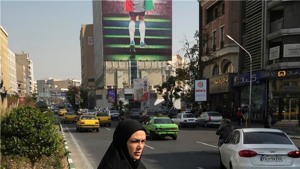 Ein Plakat zeigt einen Fußballspieler mit der Nationalflagge an einem Gebäude in Teheran.