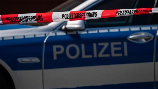 Ein Polizeiauto steht hinter einem Absperrband der Polizei.