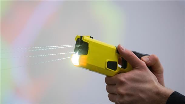 Ein Polizeibeamter demonstriert einen Schuss mit einem Taser. Das Gerät sendet nach Abschuss zweier Elektroden Stromimpulse ab.