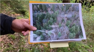 Ein Polizeibeamter hält ein Drohnen-Bild in der Hand.