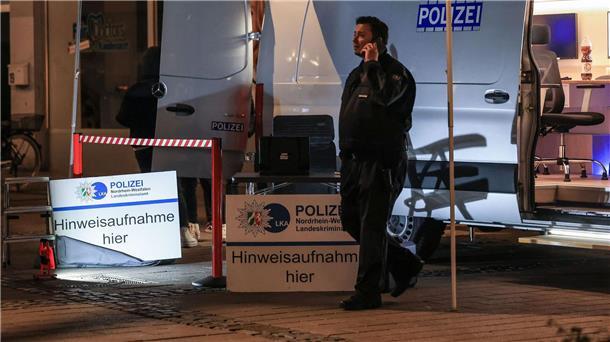 Ein Polizist steht in der Nähe des Tatortes vor einem Einsatzfahrzeug.