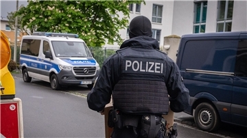Ein Polizist trägt bei einem Einsatz in Bonn einen Karton mit beschlagnahmtem Material aus einem Gebäude.