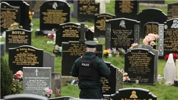 Ein PSNI-Polizist patrouilliert auf dem Stadtfriedhof von Londonderry. Kurz vor der Ankunft von US-Präsident Biden in Nordirland fand die Polizei dort vier mutmaßliche Rohrbomben.