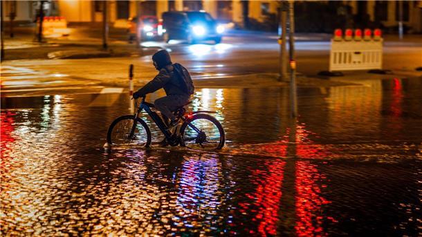 Schwere Sturmflut setzt der Ostsee-Küste zu - Eine Tote Ein Radfahrer fährt durch das Hochwasser am Stadthafen von Wismar.