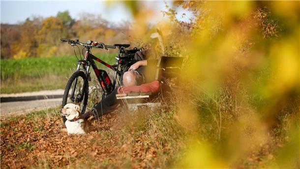 Ein Radfahrer und sein Hund sonnen sich auf der Schwäbischen Alb.