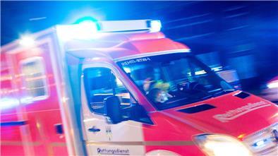 Ein Rettungswagen der Feuerwehr fährt mit Blaulicht durch eine Straße.