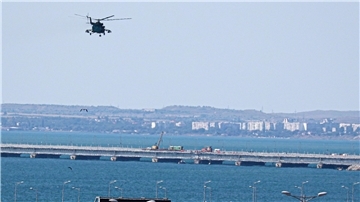 Ein russischer Militärhubschrauber überfliegt die beschädigten Teile einer Automobilverbindung der Krim-Brücke.