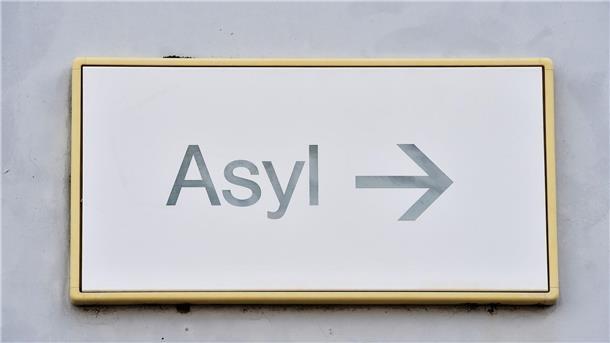 Ein Schild mit der Aufschrift „Asyl“ hängt an einer Wand.