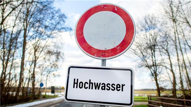 Ein Schild mit der Aufschrift „Hochwasser“ steht vor einer gesperrten Straße.