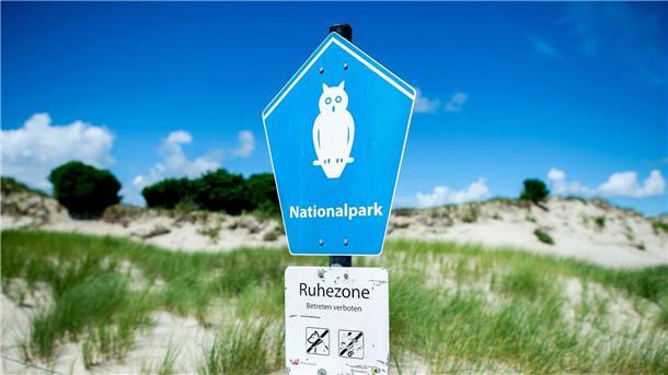 Ein Schild mit der Aufschrift „Nationalpark“ steht vor der Dünenlandschaft am Ostende der Insel Norderney.