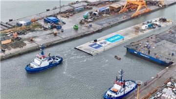 Ein Schlepper zieht das riesige Betonelement aus dem Dock.