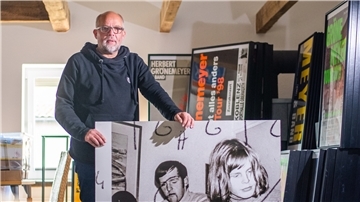 Ein Mann steht in einem großen Raum mit einem Plakat in der Hand.