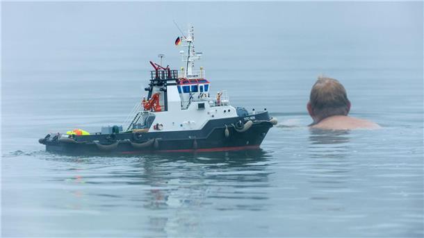Bilder des Tages Ein Schwimmer und ein Modellboot in Form eines Schleppers sind im Nebel im Schwarzachtalsee unterwegs.