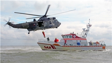Ein Seenotrettungskreuzer bei einer Übung mit einem Hubschrauber der Deutschen Marine.