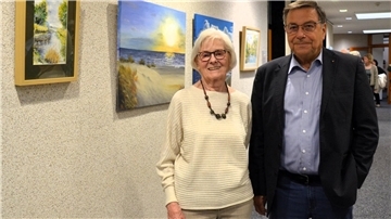 Eine Frau und ein Mann stehen vor mehreren an einer Wand aufgehängten Bildern