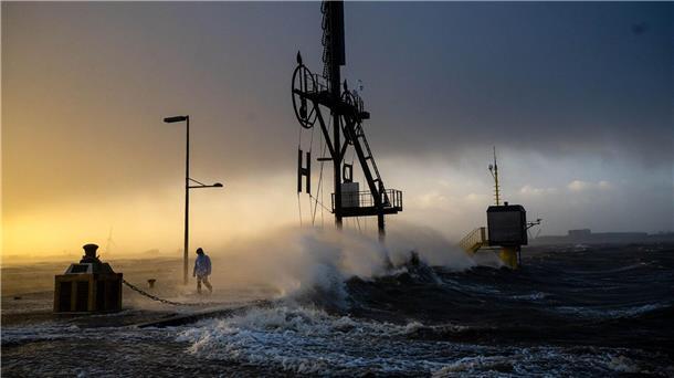 Nach Sturmtief: Heftige Regenfälle und Schnee erwartet Ein Spaziergänger läuft bei Sturmflut und Wellen am Ufer der Wesermündung in Bremerhaven entlang.