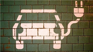 Ein Symbol markiert einen Parkplatz mit einer öffentlichen Ladesäule für Elektroautos.