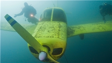 Ein Taucher schwimmt um ein versenktes Flugzeug 