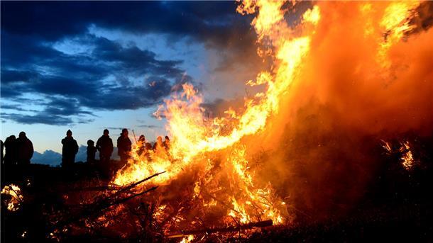 Menschen stehen um ein Osterfeuer