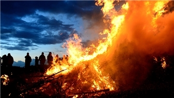 Menschen stehen um ein Osterfeuer