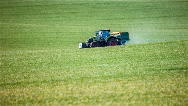 Ein Traktor mit einem Streuaufsatz verteilt Dünger auf einem Feld. Viele Landwirte haben mit massiv gestiegenen Kosten für Düngemittel zu kämpfen.