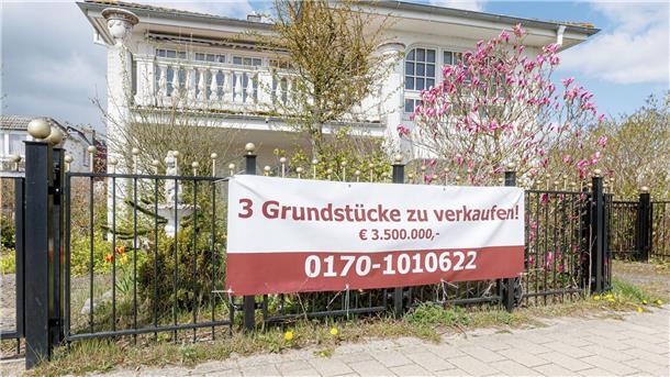Immobilienpreise an Nord- und Ostsee sinken vielerorts Ein Transparent mit der Aufschrift „3 Grundstücke zu verkaufen! €3.500.000“ hängt an einem Grundstück.