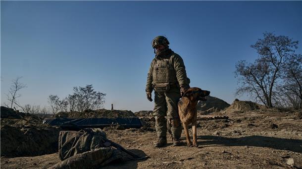 Krieg gegen die Ukraine: So ist die Lage Ein ukrainischer Soldat steht mit seinem Hund an einem Graben in Bachmut.