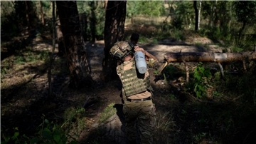 Ein ukrainischer Soldat trägt eine Granate in Richtung einer Haubitze an der Frontlinie bei Lyman.