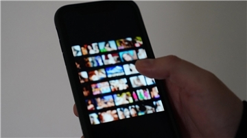  Ein Mann schaut sich auf einem Smartphone Fotos von Frauen an 