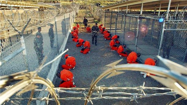 Die letzten Gefangenen von Guantánamo Ein von der US-Armee herausgegebenes Foto aus dem Jahr 2002 zeigt in orangefarbene Overalls gekleidete Häftlinge, die im Camp X-Ray auf dem Boden knien.