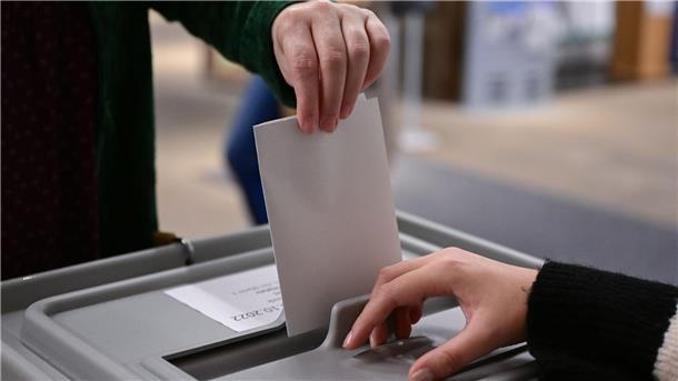 Bremen: Rekord bei Wahlberechtigten mit Migrationsgeschichte Ein Wähler steckt seinen Wahlzettel in eine Urne.