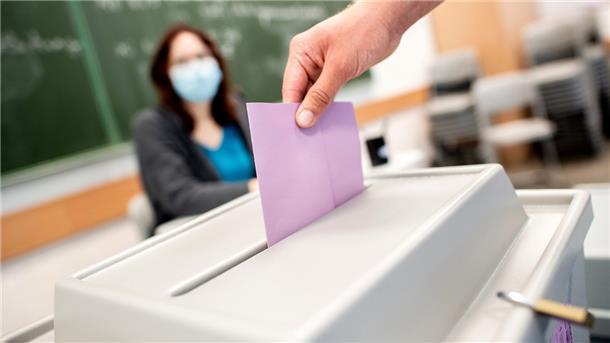 Ein Wähler wirft in einem Wahllokal, das im Klassenraum einer Schule untergebracht ist, seinen Stimmzettel für die Kommunalwahl in die Wahlurne.