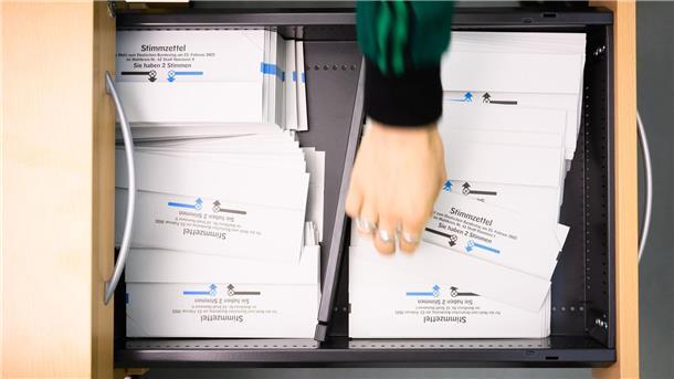 Ein Wahlhelfer nimmt in der Briefwahlstelle im Neuen Rathaus Hannover einen Stimmzettel für die Bundestagswahl 2025.