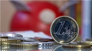 Eine 1-Euro-Münze steht vor einem Sparschwein. 