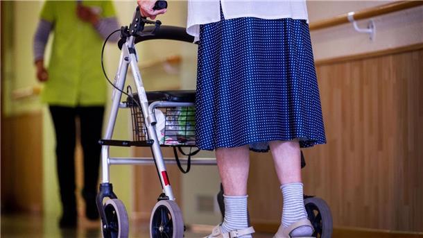 Pflege im Heim deutlich teurer - Druck für Entlastungen Eine ältere Dame geht mit ihrem Rollator über einen Flur.