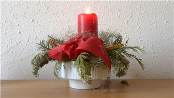 Eine brennende Kerze in einem vertrockneten Weihnachtsgesteck bedeutet Brandgefahr. dpa