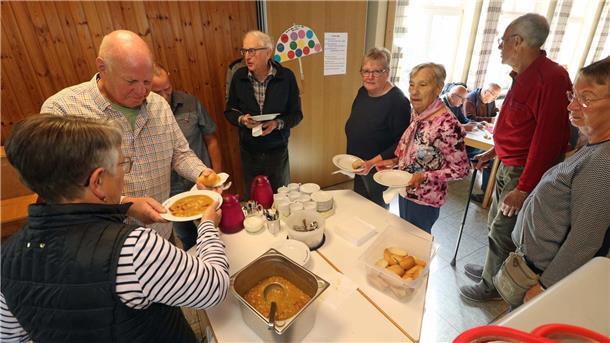 Mehrere Menschen stehen für einen Teller Suppe an